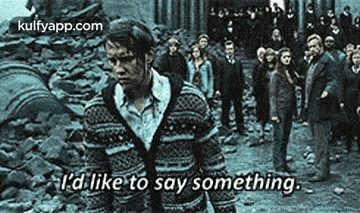 a man in a sweater is standing in front of a crowd .