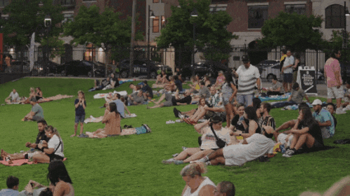 a group of people laying on the grass with one man wearing a t-shirt that says ' a ' on it