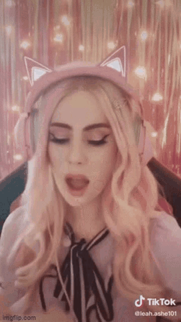 a woman wearing a pink cat ear headset is covering her face with her hands .