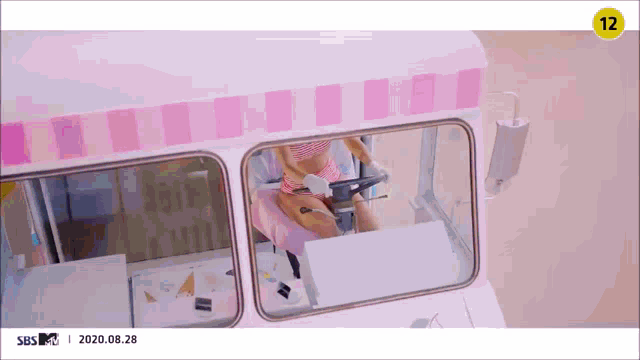 a woman is riding an ice cream truck in a pink and white striped bikini .