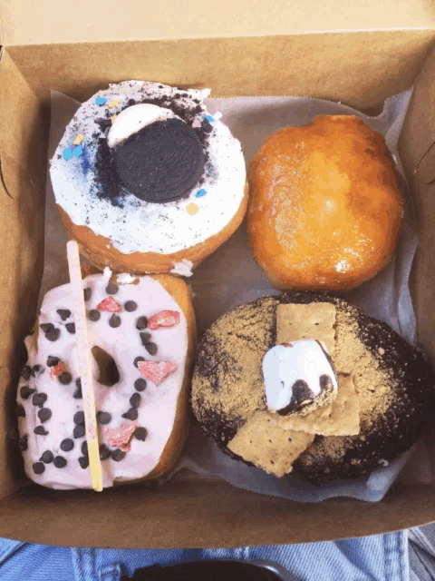 a box filled with four different types of donuts including a s'mores donut