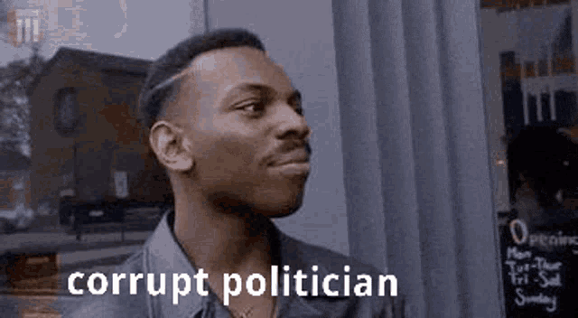 a man is standing in front of a window with the words corrupt politician written on the bottom .