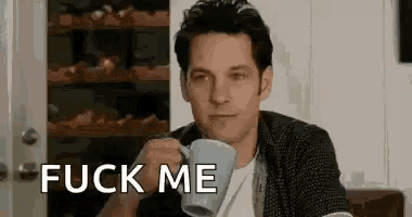 a man is drinking a cup of coffee while sitting at a table .