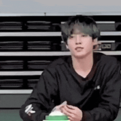 a young man in a black shirt is sitting in front of a row of black boxes .