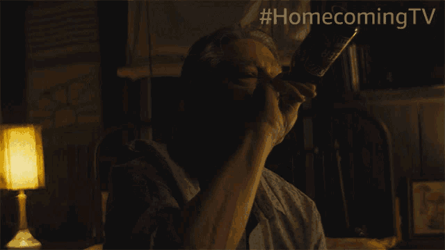 a man drinking from a bottle with the hashtag #homecoming tv behind him