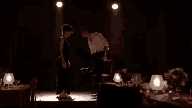 a man and woman are dancing in a dark room