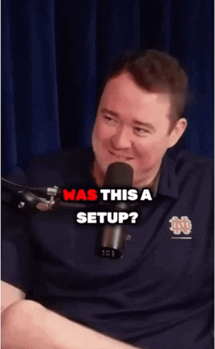a man sitting in front of a microphone with the words " was this a setup "