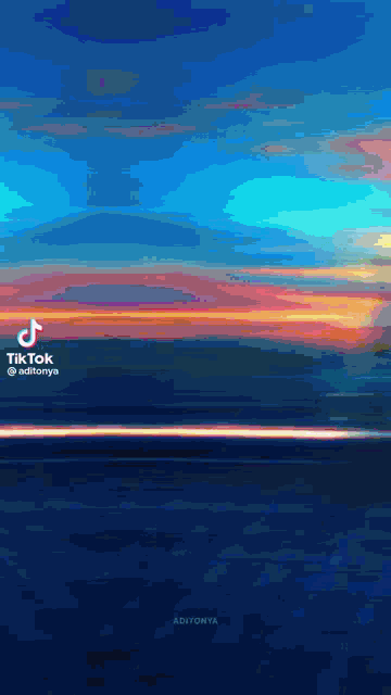a sunset over a body of water with a blue sky and orange clouds