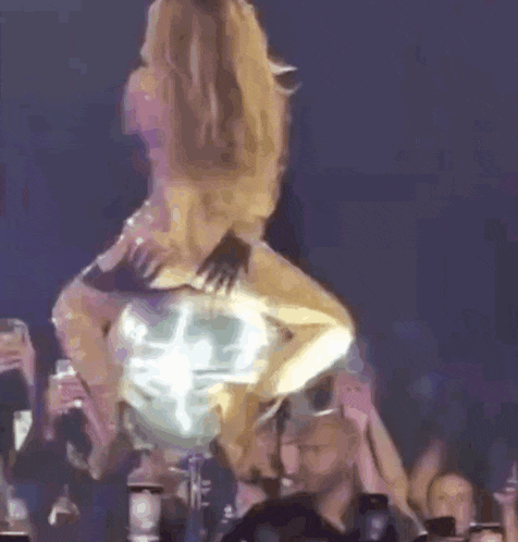 a woman in a gold dress is dancing on a stage