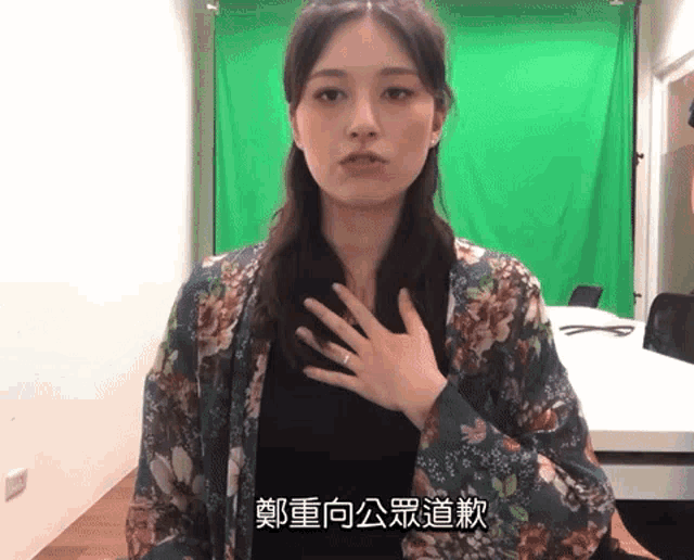a woman in front of a green screen has chinese writing on her chest