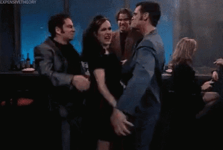 a group of people are dancing in a club while a man looks on .