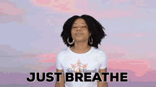 a woman with her eyes closed is wearing a t-shirt that says just breathe on it .