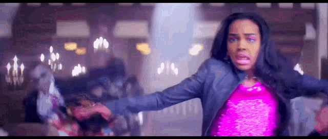 a woman in a pink top and a denim jacket is dancing in a room .
