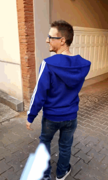 a man wearing a blue hoodie with white stripes on the sleeves