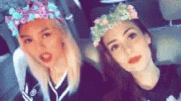 two women are sitting next to each other in a car wearing flower crowns .