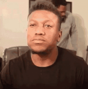 a man in a black shirt is sitting in a chair with his eyes closed .