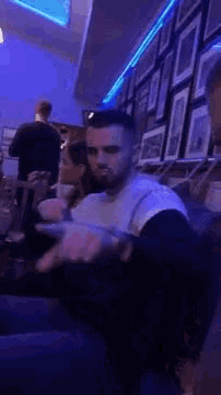 a man is sitting on a couch in a dark room holding a cigarette in his hand .