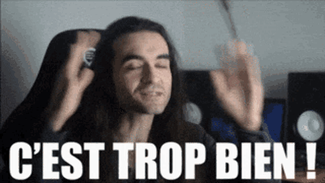 a man with long hair is holding a microphone and says " c'est trop bien "