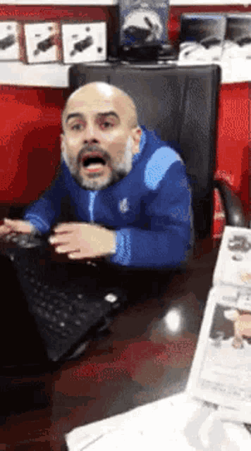 a man with a beard is sitting in front of a laptop computer