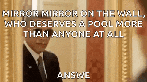 a man in a suit and tie is looking at himself in a mirror