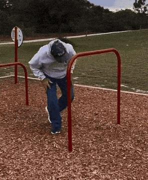 a man wearing a hat that says ' reebok ' on it is playing on a playground