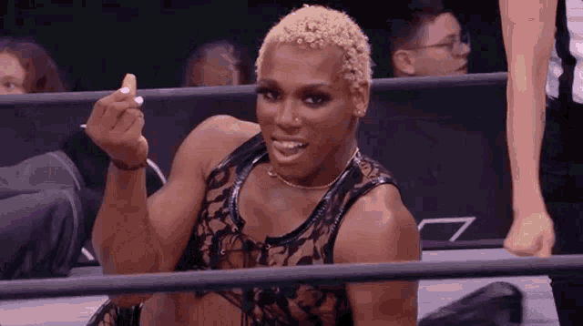 a woman is sitting in a wrestling ring making a middle finger sign .