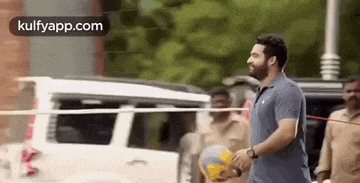 a man in a blue shirt is holding a volleyball in his hand .