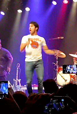 a man wearing a t-shirt that says ' hope ' on it stands on a stage