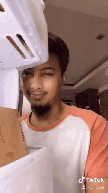 a man with a beard is holding a cardboard box and a white basket over his head with a tiktok watermark