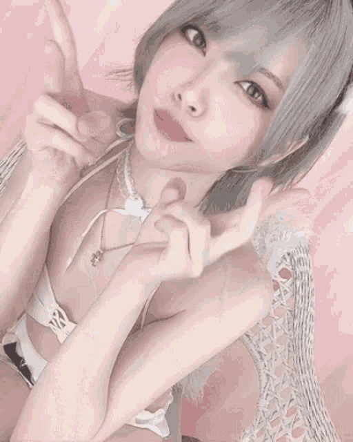 a girl in a white bikini is giving a peace sign