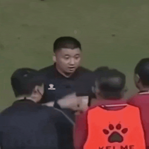 a soccer referee is talking to a group of players on the field .