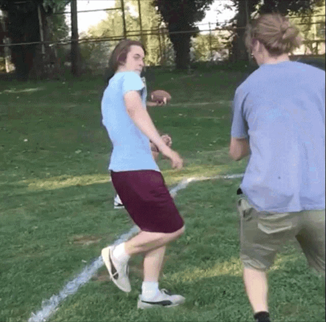 a man in a blue shirt is kicking a ball in a field