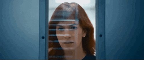 a woman with red hair is looking through a doorway .