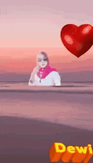 a woman in a hijab is sitting in front of a floating heart .