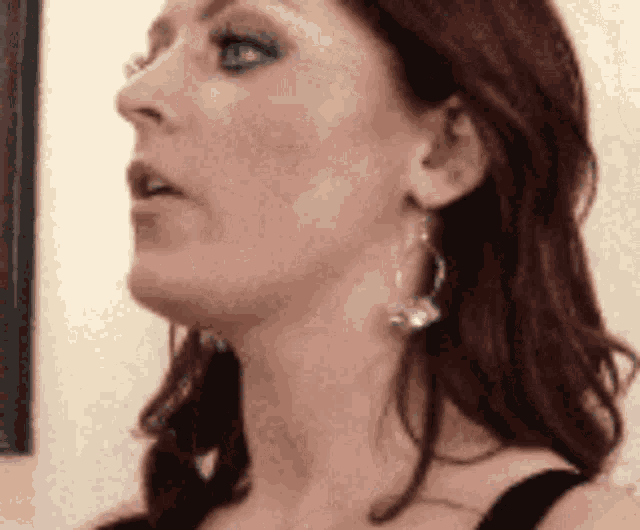 a close up of a woman wearing earrings and a black tank top