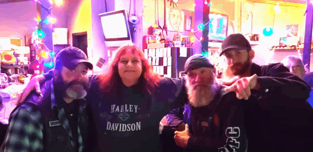 a woman wearing a harley davidson sweatshirt poses with her friends