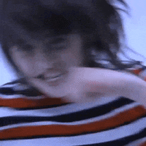 a blurry picture of a woman wearing a striped shirt with her hair blowing in the wind .