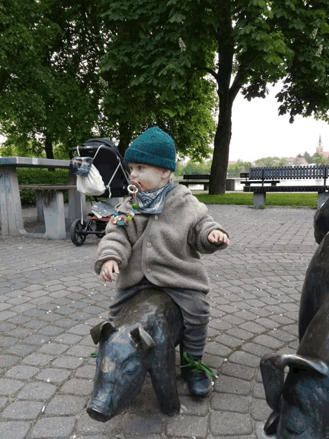 a little boy is sitting on a statue of a pig