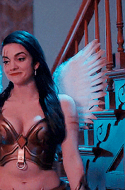 a woman in a costume with angel wings is standing in front of stairs .