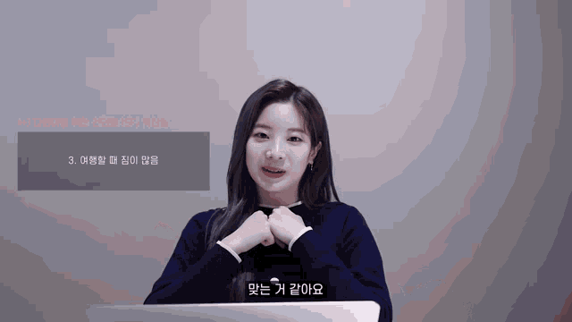 a woman in a black sweater stands in front of a screen that says ' 3 '