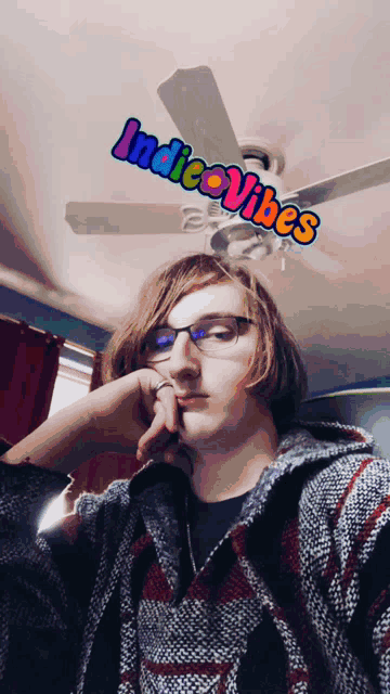 a man wearing glasses is taking a selfie with the words indie vibes above him