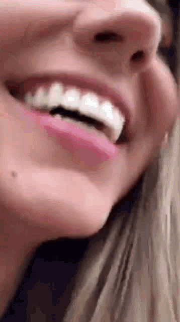 a close up of a woman 's face with her mouth open and her teeth showing .