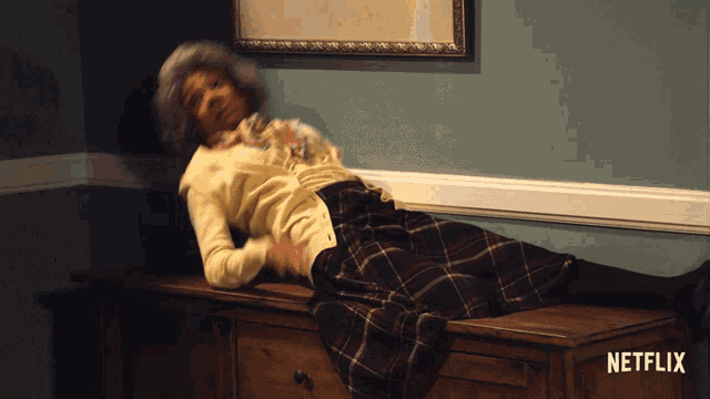 a woman in a plaid skirt is laying on a dresser with netflix written on the bottom