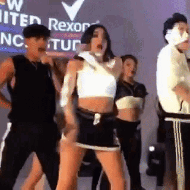 a group of people are dancing on a stage in front of a sign that says united rexor