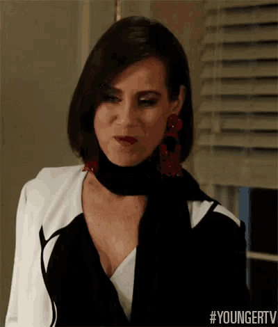 a woman is wearing a black and white jacket and a scarf around her neck .