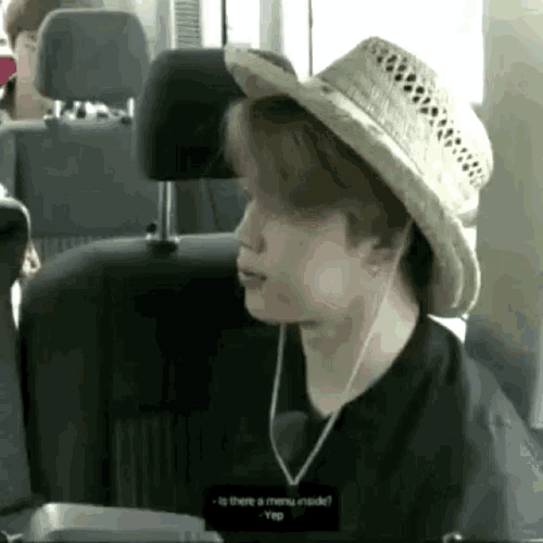 a man wearing a straw hat and earphones is sitting in a car .
