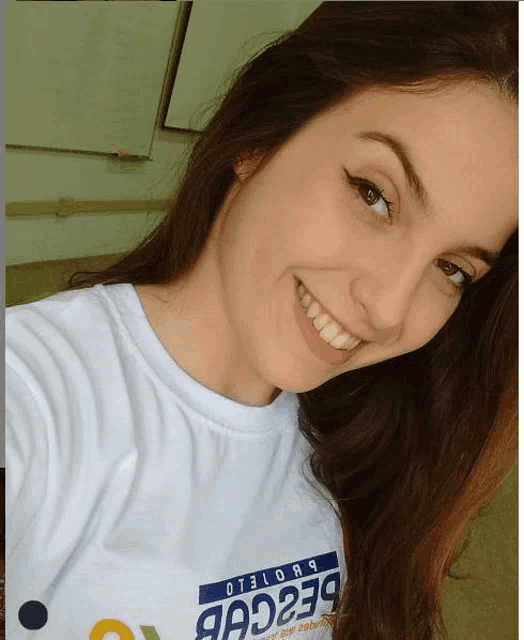 a woman wearing a white shirt that says 9a229 smiles