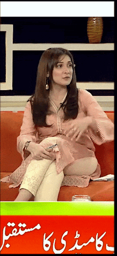 a woman sits on a couch in front of a sign that says ' urdu '