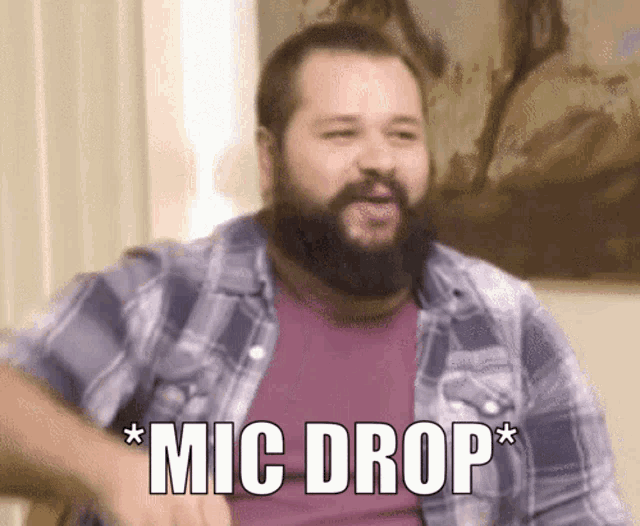 a man with a beard says " mic drop " while wearing a plaid shirt
