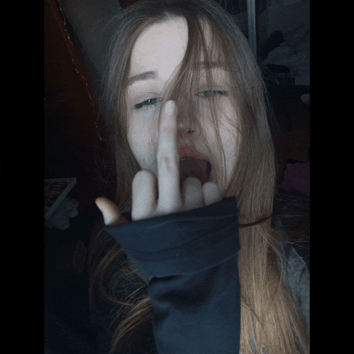 a girl with long hair is giving the middle finger to the camera